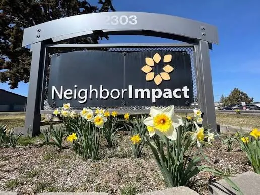 The NeighborImpact sign with daffodils in front