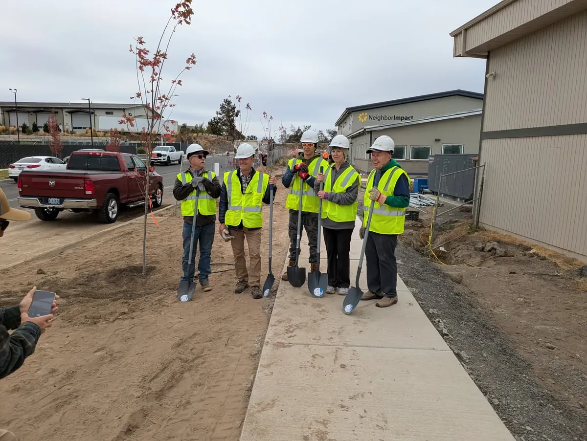 Grant and fellow volunteers in hard hats and safety vests, holding shovels at a NeighborImpact tree planting